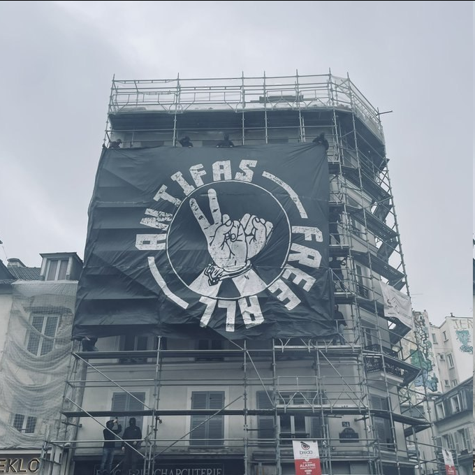 Bandierone b/n "Free All Antifas" appeso su potenggi da muratore.
Paris, 6 giugno 2026, all'angolo tra le vie (rue) Oberkampf e Saint-Maur.
